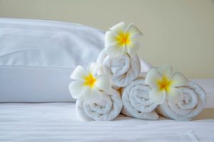 A pile of rolled up towels with flowers on top.
