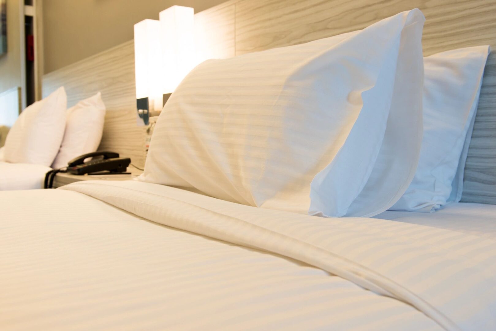 A bed with white sheets and pillows on it and lights